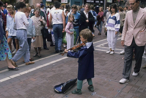 Small boy busking with his violin for an audience in Dublin