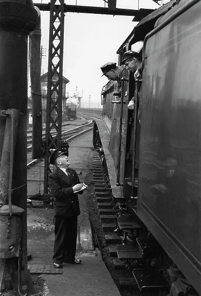 Driver and fireman consulting with station guard, c 1956