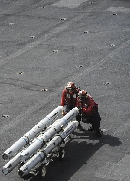 Ordnancemen push ordnance across the flight deck of USS Nimitz