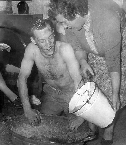 A miner, Mr. Allan Hedley, washes in a tin bath with water boiled on the only fire in