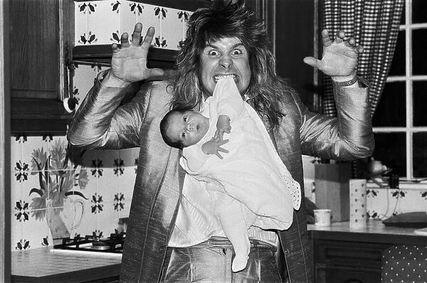 Rock star Ozzy Osbourne dangles two week old baby Jack from his teeth at his home