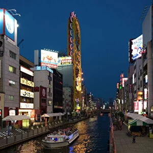 Tour boat on Dotonbori River glides past shops and restaurants in Namba
