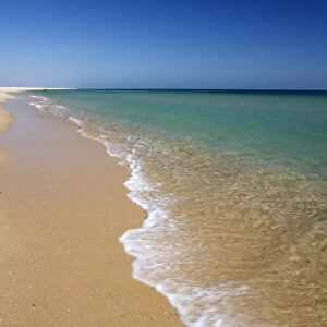 Empty white sand beach and breaking waves of crystal clear sea, Ilha do Farol, Culatra