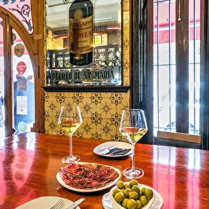 Glasses of white wine with olives and cecina dried meat served in a tapas bar of Valencia, Spain