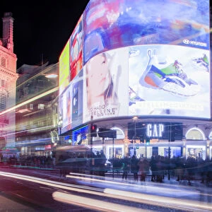 A night shot of light trails in front of the advertising hoardings in Piccadilly Circus