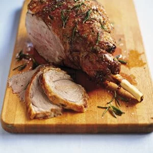 Honeyed Welsh lamb with rosemary, some slices cut away, on chopping board