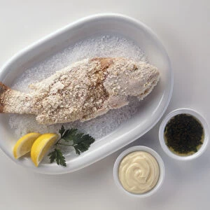 Pescado a la Sal, salted fish served with bowls of mayonnaise and parsley sauce, a typical dish from Southern Spain, view from above