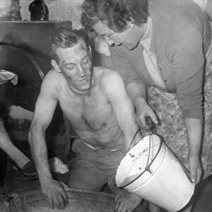 A miner, Mr. Allan Hedley, washes in a tin bath with water boiled on the only fire in